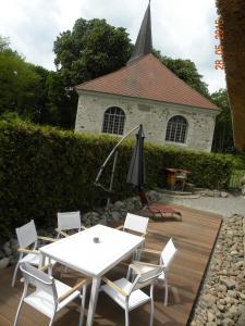 a patio with a table and chairs and a church at Historisches Küsterhaus Reetdachträume in Putzar
