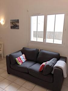 a black couch in a living room with two windows at Residence Plage Oceane in Biscarrosse-Plage