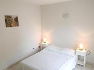 a white bedroom with two tables with lamps on them at Residence Plage Oceane in Biscarrosse-Plage