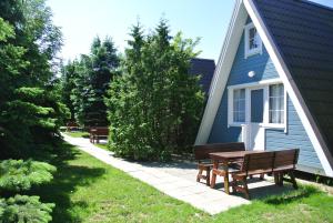 a picnic table and benches next to a house at Camping Marco Polo in Łeba