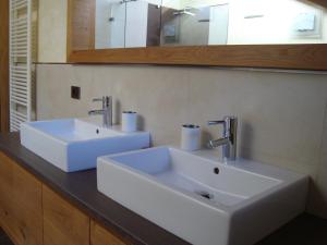 a bathroom with two white sinks and a mirror at Fiemme Deluxe Apartment in Castello di Fiemme +13 photos