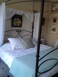 a bedroom with a black canopy bed with white sheets at L'Oustalet in La Tour-dʼAigues