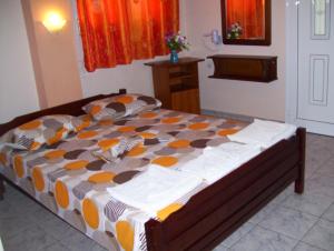 a bedroom with a bed with an orange and brown comforter at Verginia Studios in Korinós +52 photos