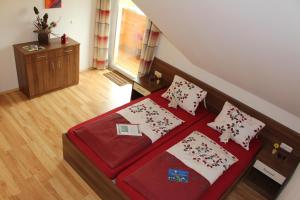 a bedroom with two beds with red sheets and pillows at Langs Wirtshaus in Sankt Ulrich im Mühlkreis