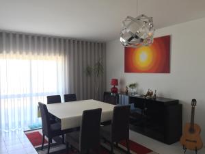 a dining room with a table and chairs and a guitar at Casa na Praia in Póvoa de Varzim