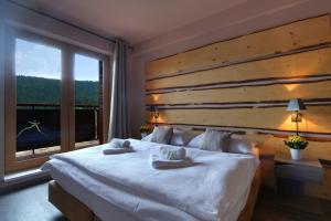 a bedroom with a large white bed with a large window at Hotel Obzor in Pec pod Sněžkou