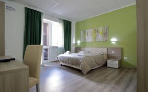 a bedroom with a bed with green walls and a chair at Nidi di Feo in Lecce