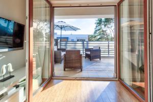 a glass door leading to a patio with a table and an umbrella at Apartament Słoneczny in Międzywodzie