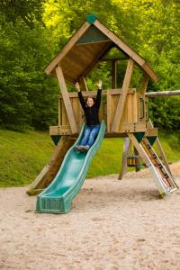 una persona che cavalca uno scivolo su un parco giochi di Self-check-in Ferienwohnungen & Apartments am Bergsee a Triberg