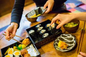 Araiya Tokyo -Private Townhouse- في طوكيو: مجموعة من الناس يأكلون السوشي على طاولة