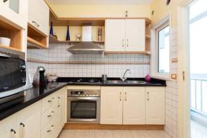 a kitchen with white cabinets and a stove top oven at Piso Centrico Y Acogedor in Las Lagunas