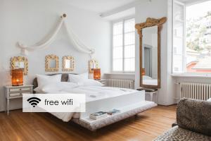 een witte slaapkamer met een wit bed en een spiegel bij Caffè dell'Arte Boutique Rooms in Locarno