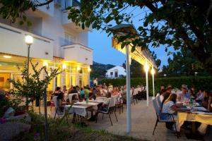 un grupo de personas sentadas en mesas en un restaurante por la noche en Pansion Burin, en Baška