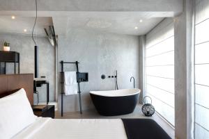 a bathroom with a large tub and a large window at Poseidon Athens Hotel in Athens