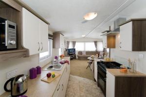 a kitchen with white cabinets and a stove top oven at Caravans Tattershall Lakes in Tattershall