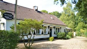 een wit huis met een bord ervoor bij B&B Ferme Knaapen in Neeritter