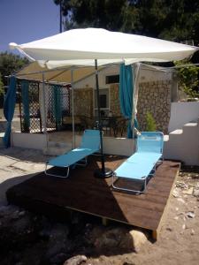 two blue chairs under an umbrella on a deck at Bluetopia studio in Skala Kallirachis