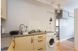 a kitchen with a sink and a washing machine at Shirley Apartments, Cozy Studio, Self Check in, 10 min Drive to City Centre, Walking to Redbridge Train Station in Southampton