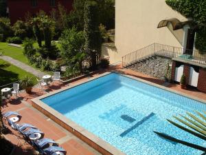 a large swimming pool with chairs and a building at Romantik Hotel Castello Seeschloss in Ascona