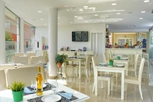 Palapart Gikas House في جوفيا: غرفة طعام مع طاولات بيضاء وكراسي بيضاء