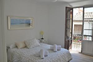 グラナダにあるLa Casa Junto a la Catedralの白いベッドルーム(タオル付きのベッド付)