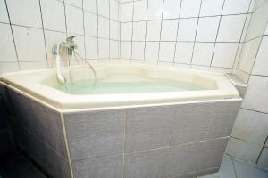 e bagno con vasca e rubinetto. di 知本溫泉の旅宿 a Wenquan