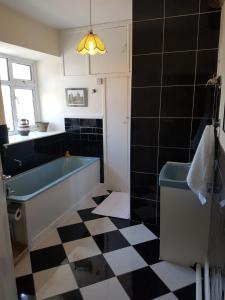 a bathroom with a tub and a black and white checkered floor at Bridge House in Carrick on Shannon