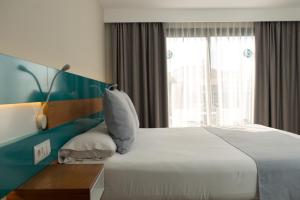 a bedroom with a large white bed and a window at Vanilla Garden Boutique Hotel - Adults Only in Playa de las Americas