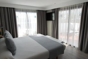a bedroom with a white bed and large windows at Vanilla Garden Boutique Hotel - Adults Only in Playa de las Americas