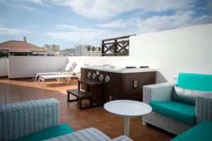 a balcony with a hot tub and chairs on a roof at Vanilla Garden Boutique Hotel - Adults Only in Playa de las Americas
