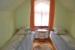 two beds in a room with a window and a table at Słoneczne Chaty pod Sonami Kasina Wielka in Kasina Wielka