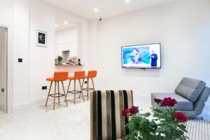 a living room with chairs and a tv on the wall at The Hurdwick in London