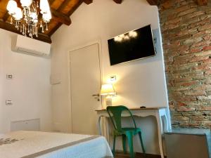 a bedroom with a green chair and a tv on the wall at Barbara’s rooms in Chioggia