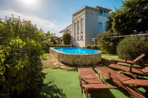 a swimming pool with wooden benches and a building at Apartments Hersones in Sevastopol