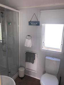 een badkamer met een douche, een toilet en een raam bij Edinburgh, Seton Sands in Port Seton