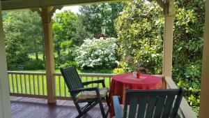 a porch with a red table and two chairs at Hummingbird Inn in Goshen