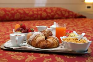 a tray of food with pastries and fruit on a bed at Hotel Excelsior in Monfalcone +33 photos