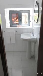 ein weißes Badezimmer mit Waschbecken und Fenster in der Unterkunft Casa do Contador T3 / T6 in Vieira do Minho + 34 Fotos