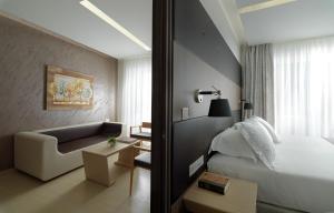 a hotel room with a bed and a chair and a couch at Melrose Rethymno by Mage Hotels in Rethymno