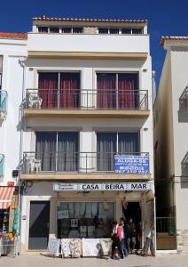 a white building with people standing outside of it at apartamentos Quebra-Mar in Nazaré