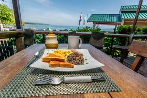 a plate of breakfast food on a table with a view of the ocean at Cabinas Arrecife in Cahuita