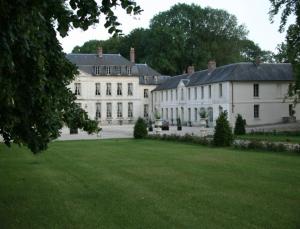 uma grande casa branca com um relvado verde em Château de Maudetour em Maudétour-en-Vexin