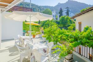 un patio con mesas y sillas blancas y una sombrilla en Hotel Theo en Panayia