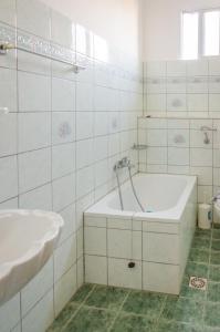 Baño blanco con bañera y lavamanos en Hotel Theo, en Panayia