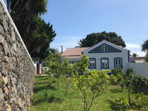 una casa azul con una pared de piedra y árboles en Silveira by the Sea, en Angra do Heroísmo