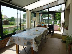 comedor con mesa, sillas y ventanas en Domisiladore en Le Molay-Littry