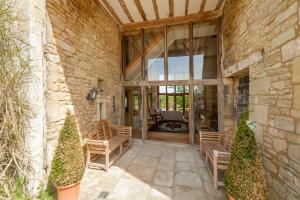 un edificio de piedra con 2 sillas y un patio en Thistle Barn en Bath