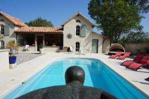a statue in front of a house with a swimming pool at Le Clos des Troubadours in Pennautier