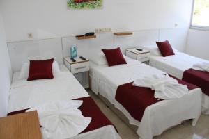 a room with three beds with red and white sheets at AELBİSTAN OTEL in Didim