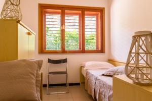 a bedroom with a bed and a chair and a window at Blue Wood Apartment in Letojanni